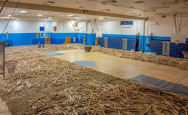 A sports hall that is being renovated. Bits of the wooden floor have been removed.